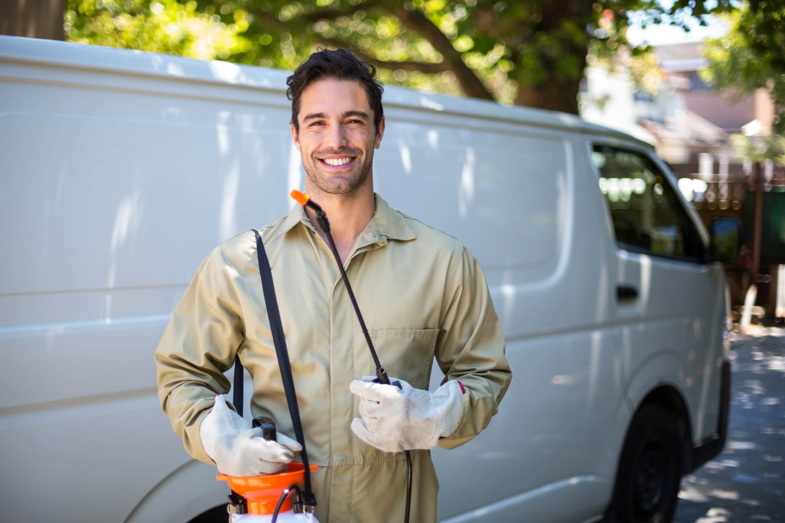 Smiling pest management worker in front of a company vehicle