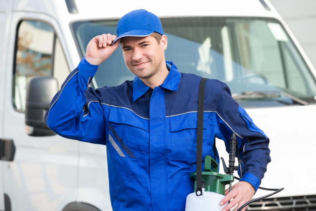 Portrait of confident pest control worker wearing cap against truck